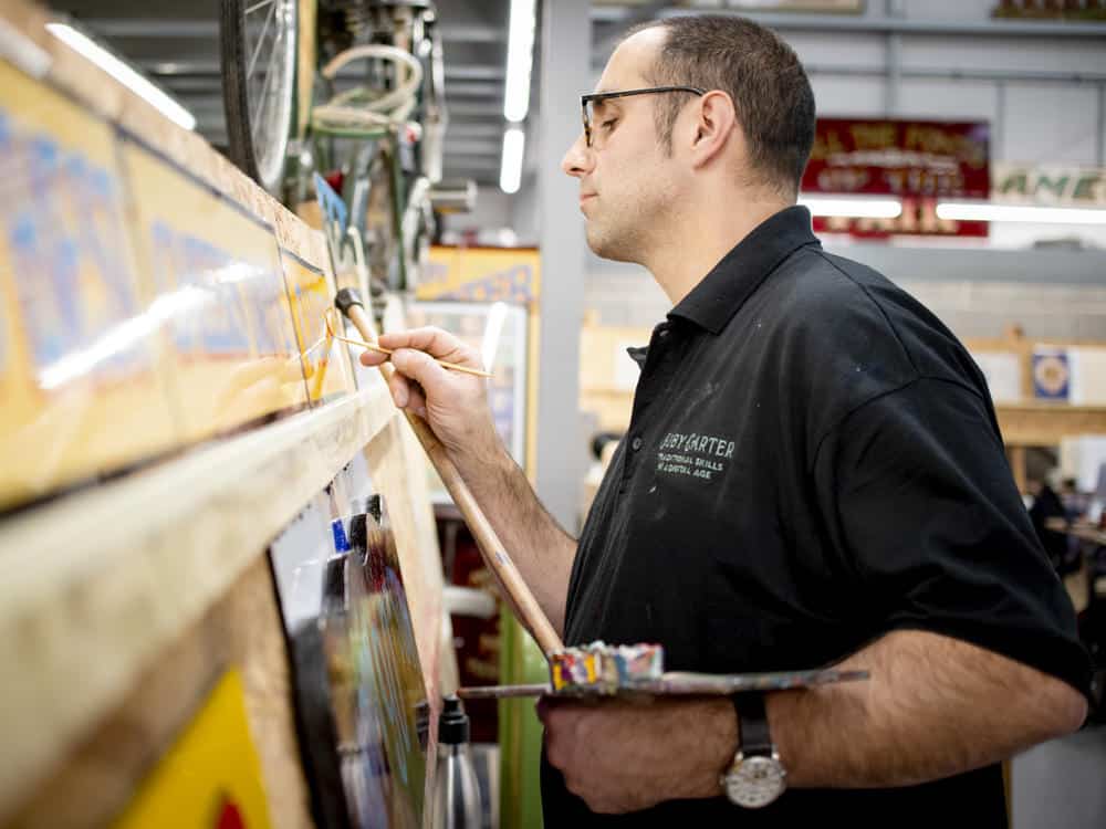 Joby Carter signwriting using a mahl stick and palette