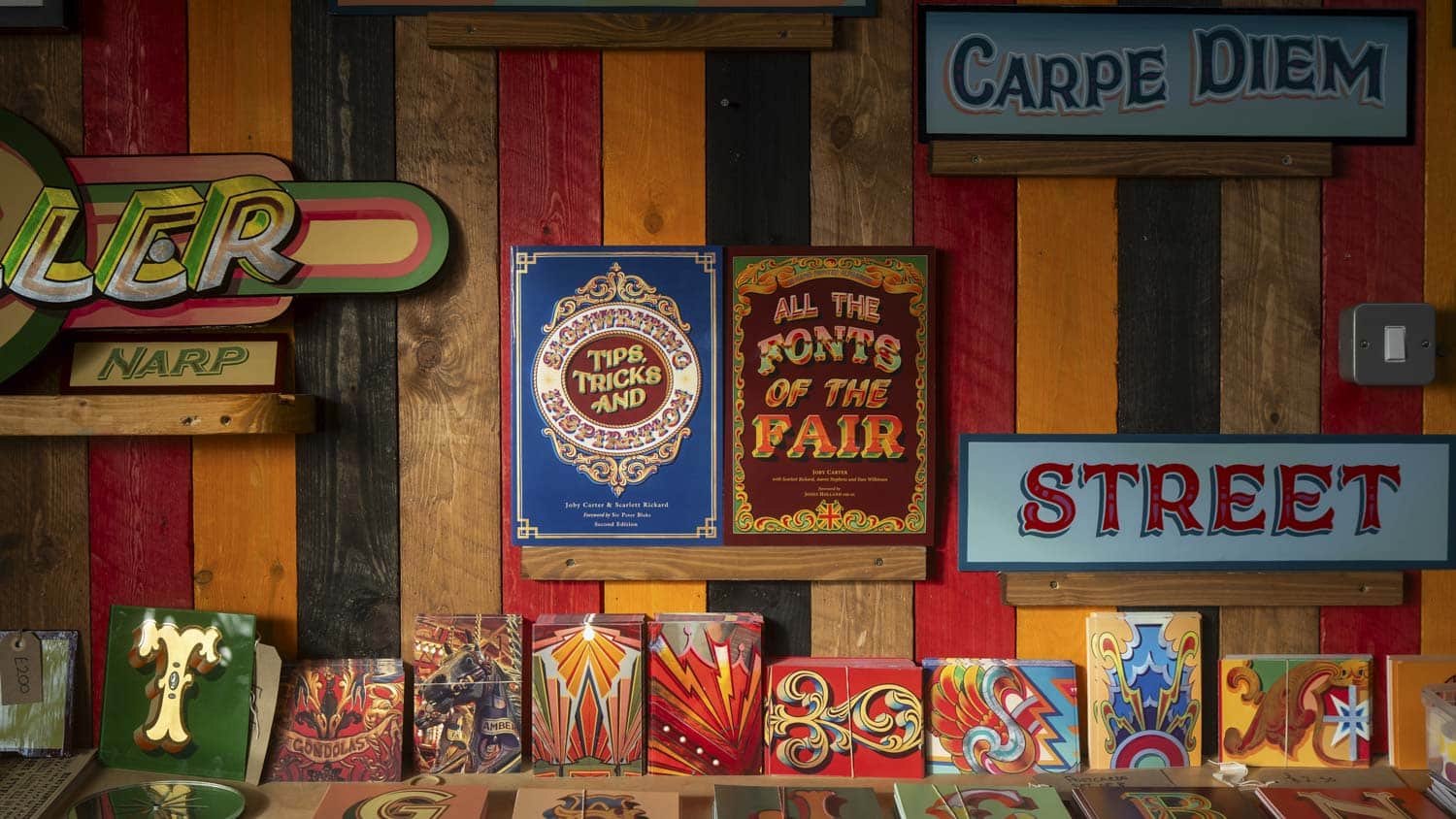 Joby Carter signwriting books on a shelf in his workshop